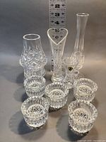 Full set of 10 Waterford crystal pieces including candle holder, votive holders, and bud vases shown together with measuring scale.