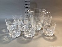 Eight crystal old fashioned glasses and one pitcher arranged together with measurement scale