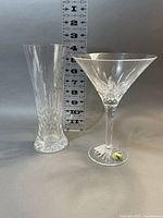 Pair of glasses – one tall pilsner and one martini – with measurement ruler behind.