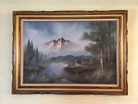 Full view of the framed landscape painting depicting mountains, trees, water, and a small building.