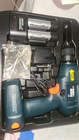 Photo showing cordless drill with attached VersaPak battery pack, charger, and drill bits in carrying case.