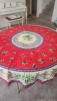 Round tablecloth with red background, olive branch and purple border design on round table