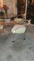 Two lucite armchairs with cream cushions positioned beside matching glass table