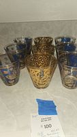 Set of 10 vintage Old Fashioned bar glasses showing two design types: gold scrolls and blue panels with gold details.