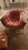 Front view of pink tufted barrel chair showing seat cushion and pillow.