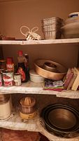 Shelving with kitchen items including electric juicer, food chopper, baking pans, canned goods, and some cooking sprays and condiments.
