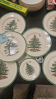 Top view of multiple Spode Christmas Tree plates showing dinner and dessert sizes with green rim and central Christmas tree graphic.