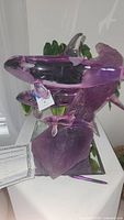 Front view of purple glass or acrylic orca sculpture with carved purple base and certificate visible.