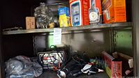Shelf with automotive charger, cables, and various grease tools in plastic bags