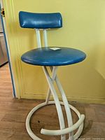 Bar stool with blue vinyl padded seat and backrest, white metal frame with circular base, visible damage on footrest section.