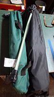 Two green camp chairs in bags and a green Cyclone Cane walking stick on a table.