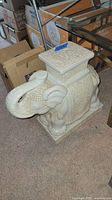 Side view of white ceramic elephant plant stand showing detailed carvings and raised trunk.