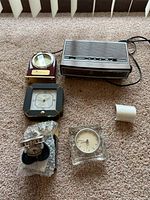 Overview of six clocks including GE AM/FM clock radio, travel clocks, and clocks in decorative cases