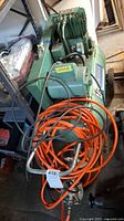 Full view of green Sears twin cylinder air compressor with orange hose and spray gun coiled on top.