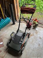 Full angled view of the Black & Decker electric mower with extension cord coiled on the handle, showing wheels and handle design.