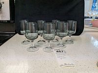 Seven Holmegaard aperitif glasses arranged in a semi-circle on a countertop.