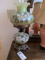 Front view of the lamp showing the hand-painted floral designs on the Bristol glass font and shade, and metal base.