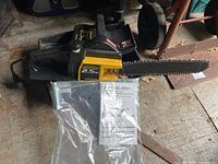 Full view of McCulloch electric chainsaw with visible yellow and black body, 2.5hp label and 13 inch blade. The chainsaw rests on a wooden surface with the user manual underneath.