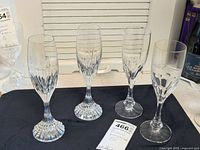 Full view of 4 Baccarat crystal stemware glasses on black cloth, showing two monogrammed and two engraved glasses.