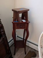 Wooden side table with drawer and wooden step stool stacked on top, showing full height and profile.