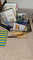Photo showing top view of box with greeting cards, batteries, wooden letter openers, neck magnifier box, flashlight