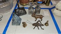 Various stone and metal animal figures including dog, cricket, and lion paperweights alongside candle holders.
