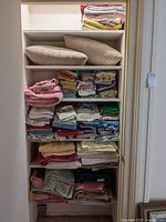 Full shelf view showing pillows and stacks of assorted towels in multiple colors and sizes.