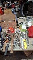 Wide view of assorted hand tools including wrenches, flashlights, a timer, and scissors arranged on a table.