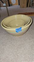 Photo showing three nesting yellowware bowls in pale yellow with pink and blue stripes stacked inside each other.