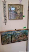 Photo of three wall art pieces: vertical needlework floral piece, framed needlework landscape, and triptych tile artwork below