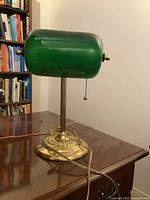 Front and angled view of the banker’s lamp showing green glass shade, brass base, and power cord.