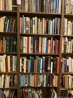 Books on wooden shelves showing multiple rows of various books with varied bindings and titles. The shelving unit is not included.