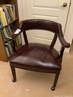 Front view of brown leather desk chair showing studded edges and wheeled legs