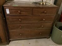 Front view of the wooden dresser showing the five drawers and two lockable drawers lacking keys.