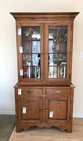 Front view of Ethan Allen two-piece cabinet showing glass paneled doors and lower drawers and cabinet doors.