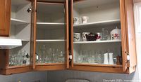 Glassware, stemware, crystal glasses, mugs, and teapots inside kitchen cabinets