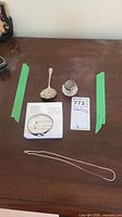 Full lot on table showing bracelet, tomato spoon, monogram jar, chain, and tags.