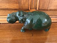 Side view of the green stone hippopotamus figurine on wooden surface.
