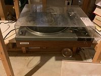 Photo of the Pioneer turntable with dust cover and wooden base.