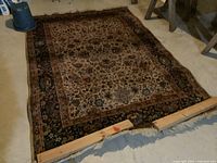 Full view of wool carpet showing overall condition and pattern, carpet laid flat with wooden blocks holding down edges.