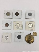 Group shot of all 10 pieces: eight coins in flips, loose Morocco coin and large medal
