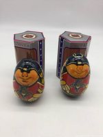 Front view of both wooden wobble dolls with their STAN'KA boxes