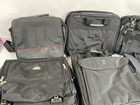 Front view showing six assorted black laptop bags arranged side by side