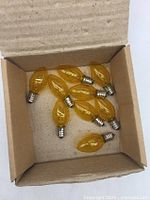 Open box showing nine transparent yellow bulbs with screw bases
