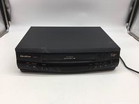 Front angled view of Quasar VHQ-940 VCR showing overall condition and attached power cord