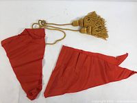 Two red triangular cloth pieces and gold tassel cord