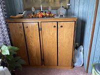 Front view of a closed brown wooden cabinet with four doors and black butt hinges showing exterior.
