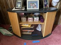 Front view of wood and glass corner shelf showing shelves behind glass doors and items placed on top