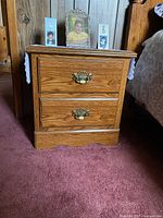 Front view of rustic night stand with two drawers, showing wood grain and brass and cream handles.