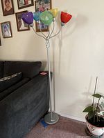 Full view of tall silver metal floor lamp base next to couch and plant.
